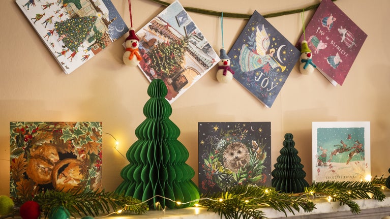 Christmas cards hang on a wall and stand on a mantlepiece